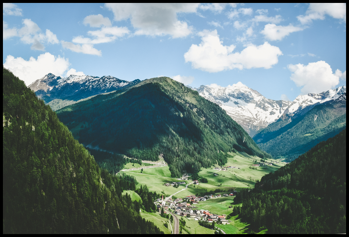 Village nestled in valley between beautiful mountain peaks. class=