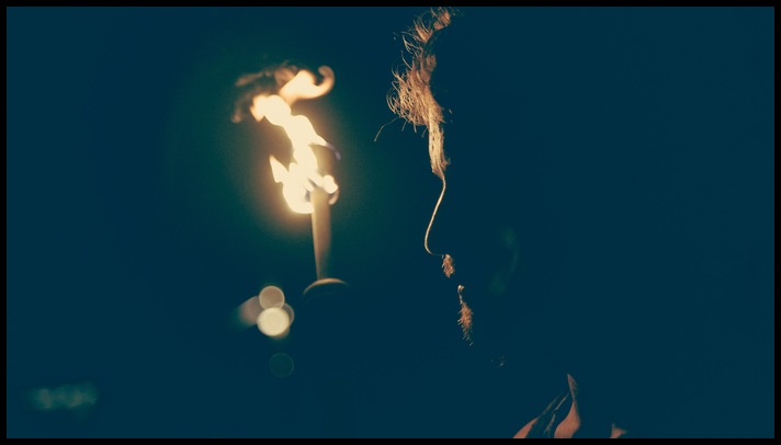 Face with a fiery torch in the background.