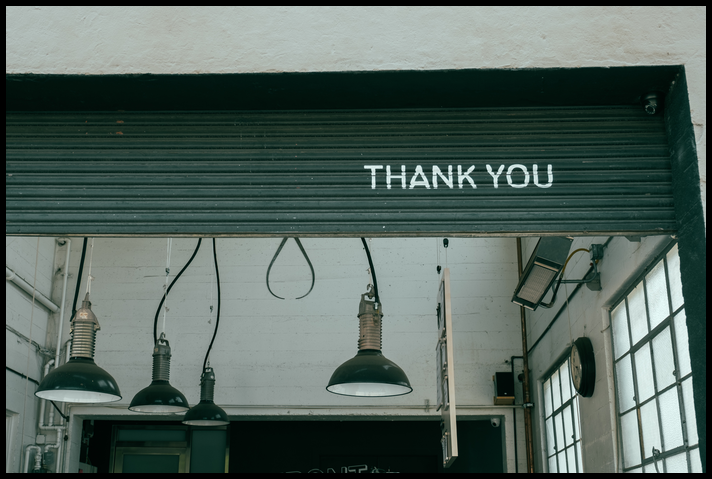 Green garage door, two-thirds up, with the stenciled words thank you visible. class=