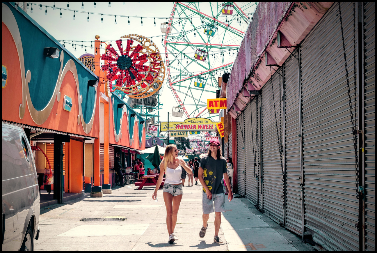 Young couple walking through a closed, colorful, carnival.